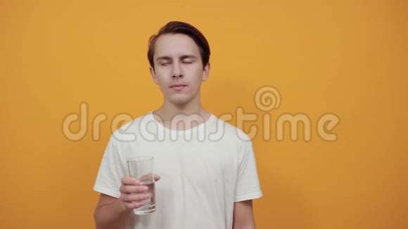 一个穿着白色t恤的男人穿着黄色背景的杯子里的饮用水视频的预览图