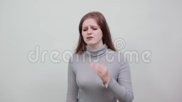 一位年轻漂亮的红发女子穿着一件灰色毛衣表现出头痛偏头痛视频的预览图