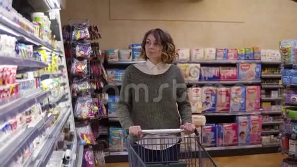食品健康概念在超市里的女人站在冰箱货架前选择买一瓶视频的预览图