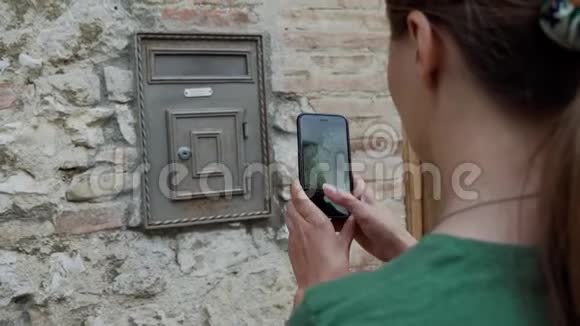 旅游女孩用手机拍老古董邮箱的照片后视图视频的预览图