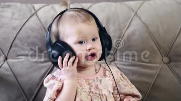 一个小女孩坐在沙发上用耳机听音乐视频的预览图