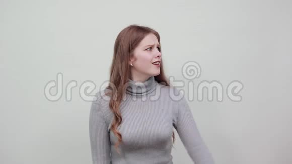 红发灰色毛衣的女人用食指指着惊恐的方向视频的预览图