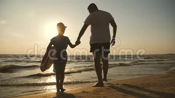 剪影父女在日落时在海滩上玩耍友好家庭旅游生活方式的概念视频的预览图