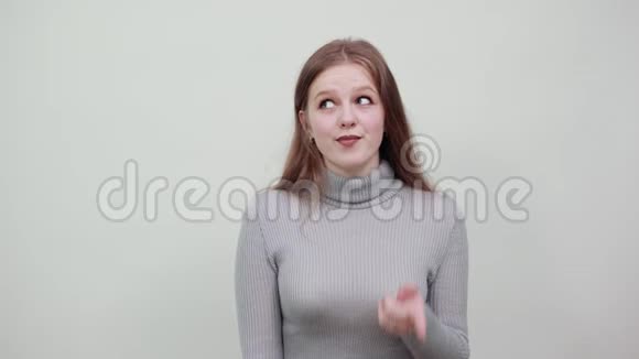 一个欧洲女孩的外表显示舌头灰色背景视频的预览图