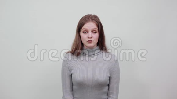 穿着灰色毛衣的红发年轻漂亮女子惊讶的样子视频的预览图