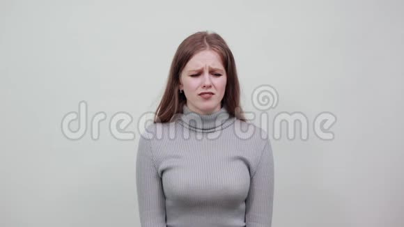 一位年轻漂亮的红头发女人穿着灰色毛衣对坏心情感到失望视频的预览图