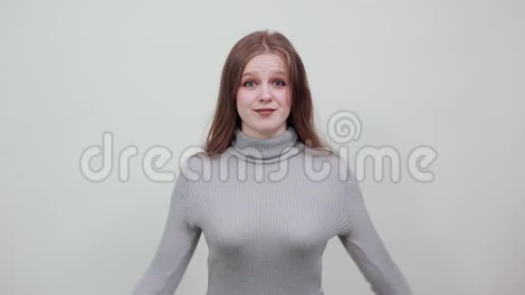 一个穿灰色毛衣的年轻红发女郎高兴地举起双手视频的预览图