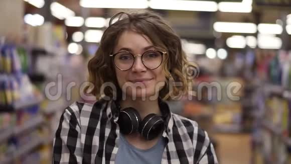肖像年轻女子站在镜头前微笑着在超市感受快乐的女孩购物脸零售店视频的预览图