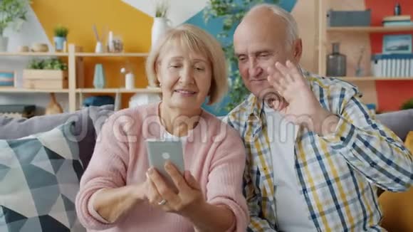 在网上打视频电话的老年人他们用拇指举起智能手机视频的预览图