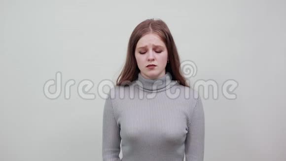 穿着灰色毛衣的年轻红发女子因肚子疼痛而身体倾斜视频的预览图