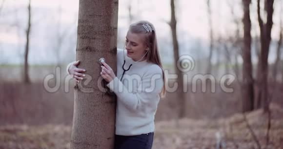 女人用听诊器检查森林里的一棵树视频的预览图