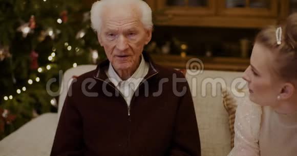 圣诞节期间和祖父在家聊天的女人视频的预览图
