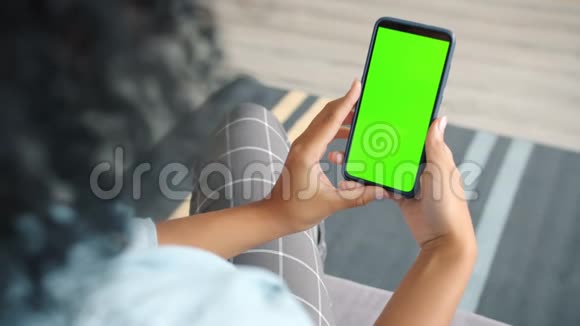 深色头发的后视图持色度键绿色屏幕智能手机观看内容视频的预览图