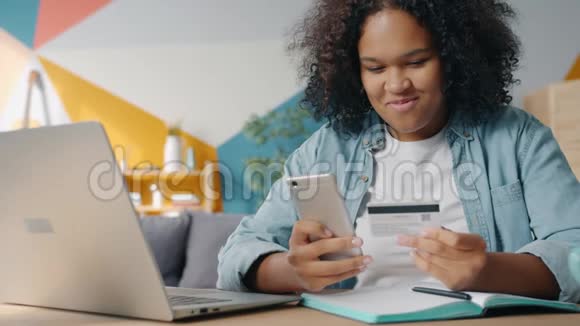 快乐的非裔美国学生用智能手机和银行卡在线购物视频的预览图