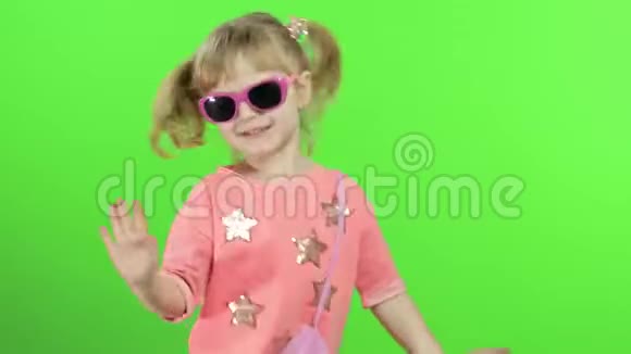 穿着粉红色衬衫和太阳镜跳舞和摆姿势的积极女孩色度键视频的预览图
