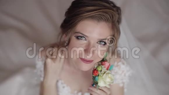 美丽可爱的新娘穿着睡衣和面纱结婚的早晨婚礼花束视频的预览图