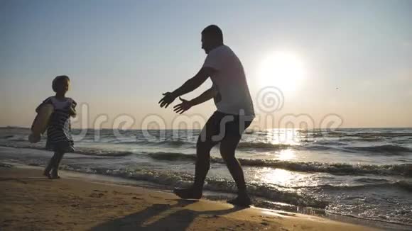 剪影父女在日落时在海滩上玩耍友好家庭旅游生活方式的概念视频的预览图