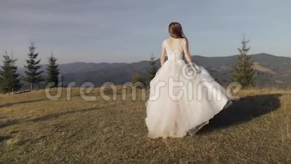 美丽可爱的新娘穿着婚纱在山坡上奔跑视频的预览图