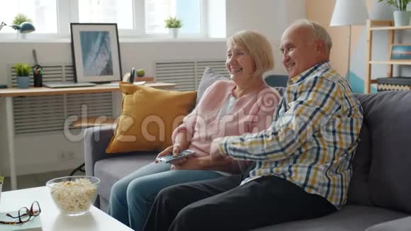 快乐的丈夫和妻子慢动作老人在家看电视笑视频的预览图