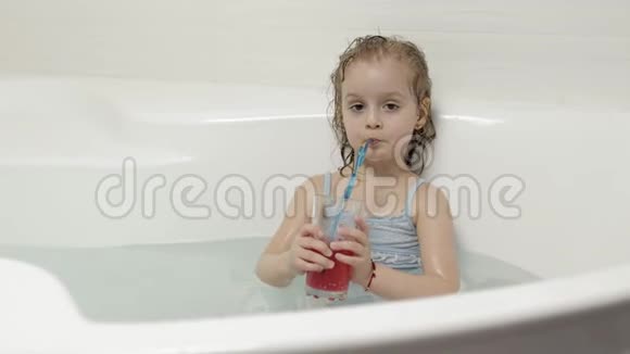 可爱的金发女孩穿着泳装洗澡喝鸡尾酒幼儿视频的预览图
