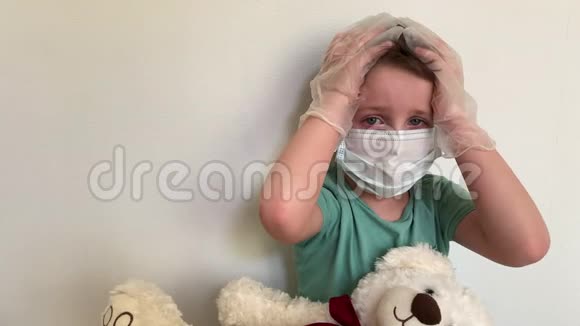 一个戴着面具戴着乳胶手套戴着泰迪熊的孩子哭着看着摄像机视频的预览图