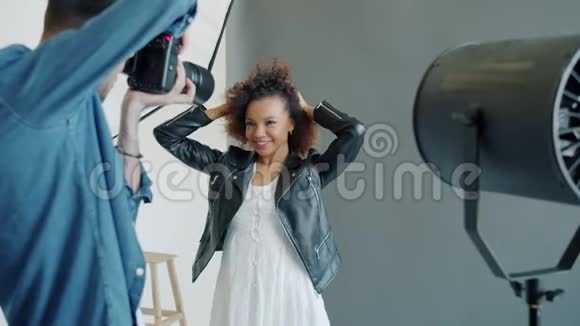 摄影师在摄影棚里拍摄快乐的非裔美国女孩模特视频的预览图