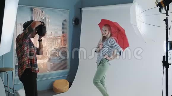 照片拍摄的幕后迷人的白种人模特用红色雨伞摆姿势视频的预览图
