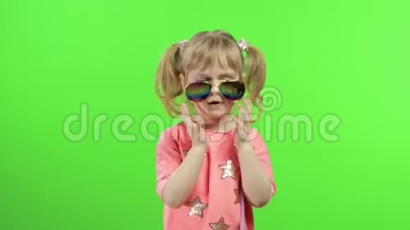 穿着粉红色衬衫和太阳镜跳舞和摆姿势的积极女孩色度键视频的预览图
