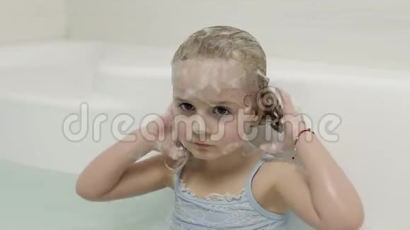 可爱的金发女孩穿着泳装洗澡小孩子洗头视频的预览图