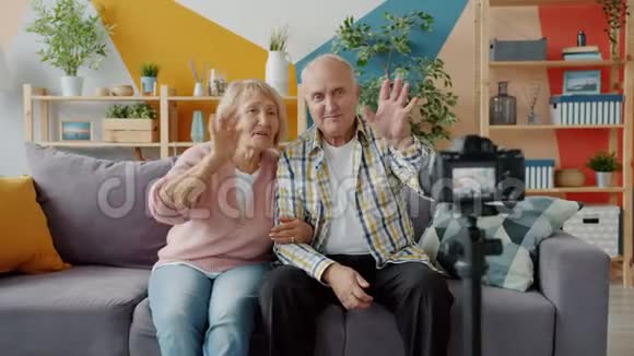 老年人博客写手在家里用摄像机记录视频打手势视频的预览图