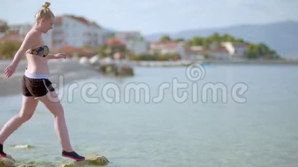 年轻的女士坐在海滩上使用她的移动设备视频的预览图