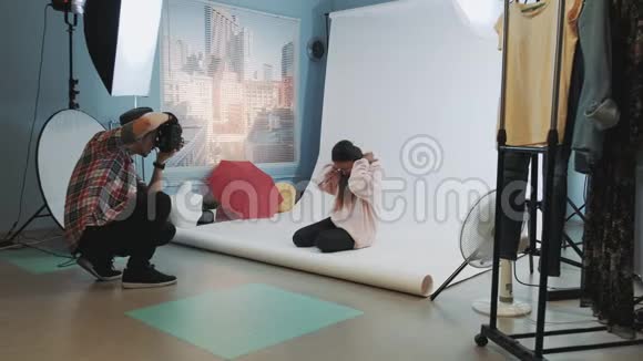照片拍摄的后台黑色模特坐在地板上为摄影师摆姿势视频的预览图