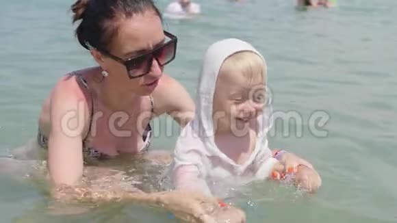 妈妈带着一个小妩媚的儿子沐浴大海家庭幸福小妈妈教小男孩游泳家庭休息视频的预览图