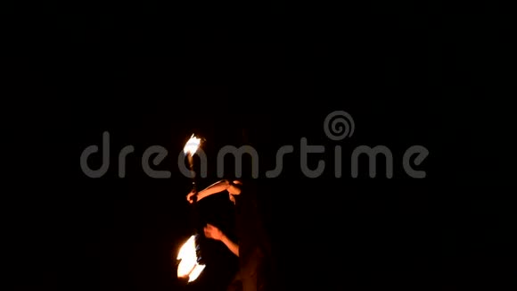 黑暗中的年轻人描绘了旋转燃烧的火炬消防表演低调视频的预览图