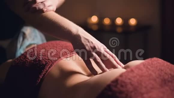一名专业理疗师按摩师在按摩豪华客房为女性患者做腰椎按摩的男性手视频的预览图