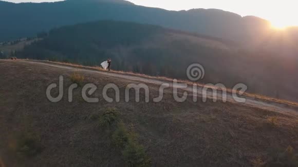 新婚夫妇在高高的山坡上跳舞新郎和新娘空中景观视频的预览图