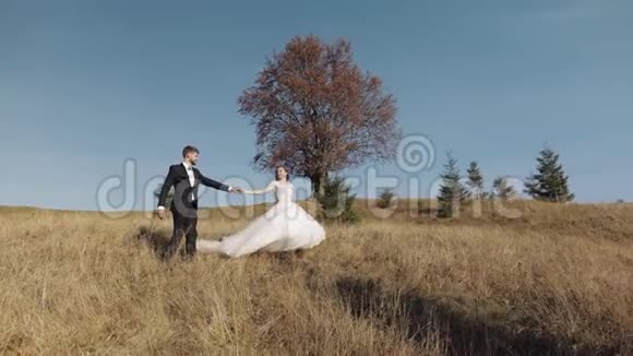 新婚夫妇白人新郎和新娘在山坡上散步新婚夫妇视频的预览图