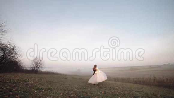 新婚夫妇在跳舞白种人新郎和新娘在晨场雾婚礼视频的预览图