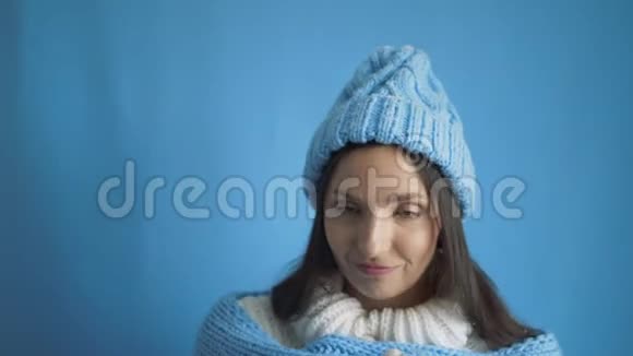 背景上穿着白色毛衣和蓝色帽子的女孩的肖像视频的预览图
