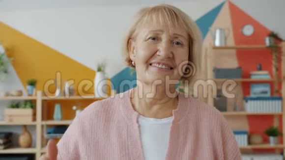 一位年长女性的慢镜头肖像独自在家中竖起大拇指的手势视频的预览图