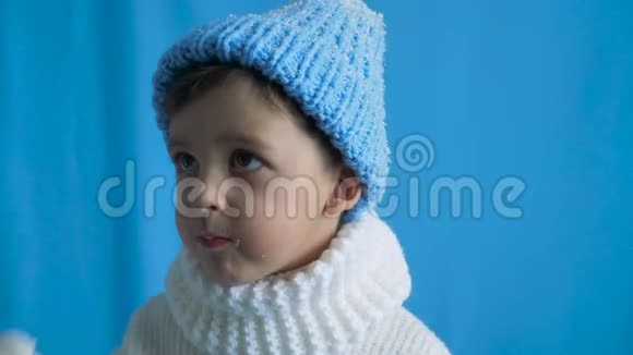 穿蓝色针织帽子和白色毛衣的儿童视频的预览图