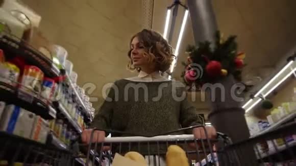 穿着便装的漂亮女人走在杂货店里手里拿着面包的购物车看上去很漂亮视频的预览图