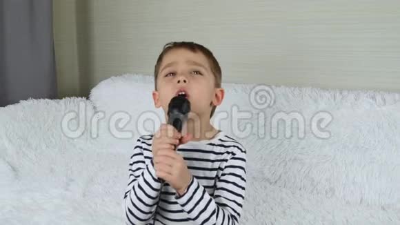 一个快乐的小男孩唱成玩具麦克风想象自己是一个歌手儿童音乐和游戏音乐视频的预览图