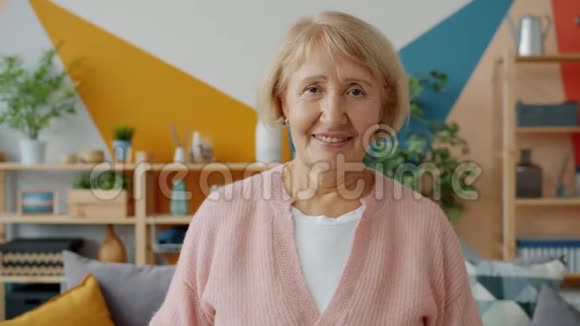 一位独自站在家中微笑的美丽退休女士的慢镜头画像视频的预览图