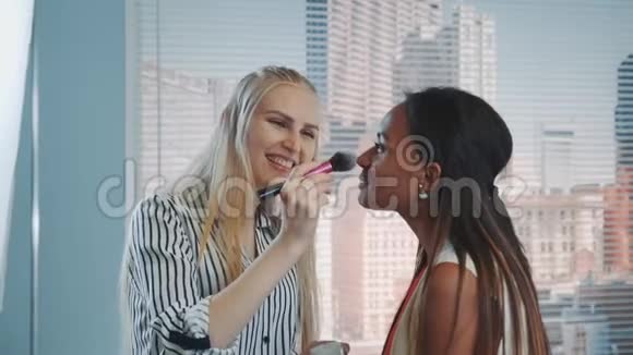 化妆师在黑色模特上化妆的特写镜头背景是摩天大楼视频的预览图