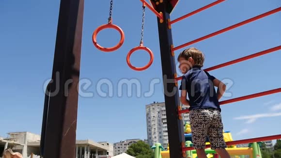 一个快乐的孩子在阳光明媚的夏日带着戒指在孩子们的游乐场玩耍幼儿户外游戏视频的预览图