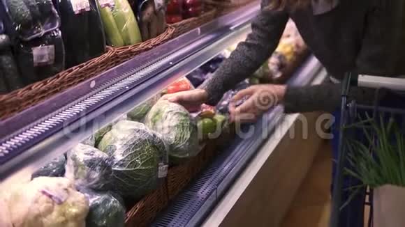 现代超市的年轻女子在有机蔬菜部门选择大白菜然后把它放到一辆手推车上健康视频的预览图