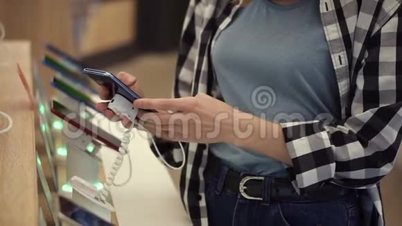 一个无法辨认的女人的腰部镜头她的手在一家电子商店里选择了一部智能手机她把智能手机从视频的预览图