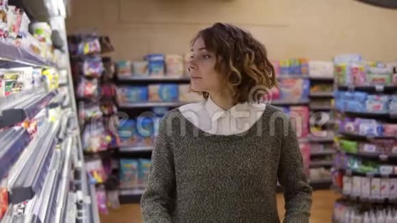 食品健康理念一个超市里的女人站在冰箱货架前选择买一瓶视频的预览图