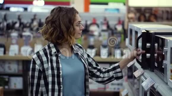 一位穿格子衬衫的卷发少女在消费电子超市里选择了微波炉视频的预览图